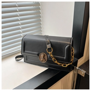 Detail of black leather crossbody bag featuring vintage gold buckle and metal chain strap