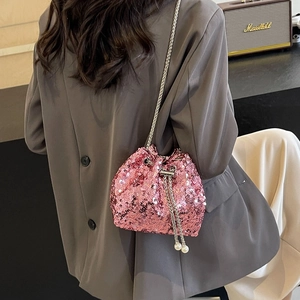 Sac seau rose à paillettes avec glands en perles et chaîne argentée porté par un modèle