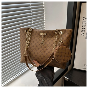 Close-up of brown vintage monogram tote bag with gold chain strap and deer pendant charm