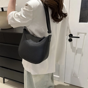 Minimalist black lychee pattern leather saddle bag with wide shoulder strap on model