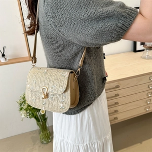 Fashionable straw crossbody bag featuring white flower embroidery and leather accents