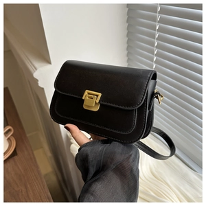 Close-up of black leather crossbody bag featuring vintage gold metal clasp and fine stitching