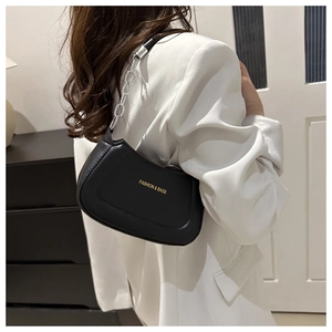 Close-up of black PU leather shoulder bag with golden text and chain strap on model