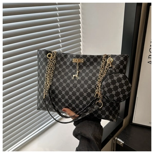 Close-up of black tote bag with clover patterns, gold deer pendant, and chain strap