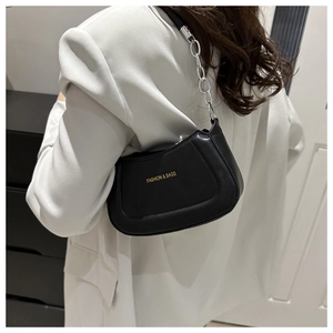 Detail showing a black semi-circular shoulder bag with silver chain strap worn by a model