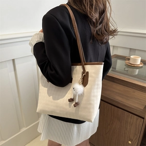 Minimalistische beige Shopper-Tasche mit braunen Riemen und süßem Puppen-Anhänger