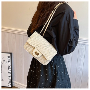 Detail of cream straw crossbody bag with green floral embroidery and gold chain