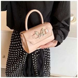 Detail of a pink glossy leather handbag featuring a silver butterfly buckle and round handle