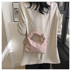 Detail of light pink pleated cloud bag with knotted handle worn over a cream blazer