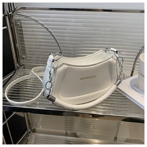 Detail of white glossy leather hobo bag with gold fashion text and silver chain strap
