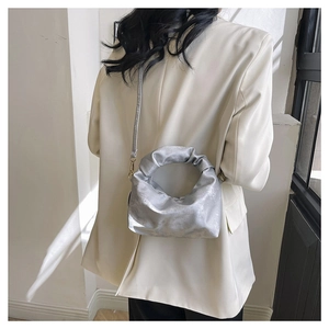 Close-up of a metallic silver pleated cloud bag with unique hollow circular handle detail