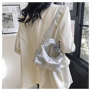 Detail view of silver pleated cloud handbag showing unique twisted handle and texture