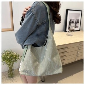 Vue détaillée du sac cabas vert clair avec texture plissée et étiquette de mode sur un mannequin