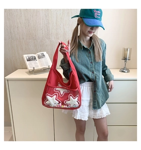 Détail du sac fourre-tout en toile rouge avec étoiles brodées et pompons colorés