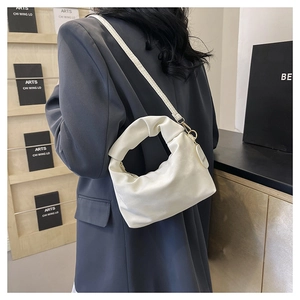 Detail of minimalist beige pleated handbag with matte texture and elegant golden hooks