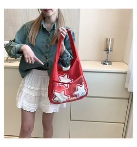 Détail du sac cabas en toile rouge avec étoiles pailletées et mini pompons colorés