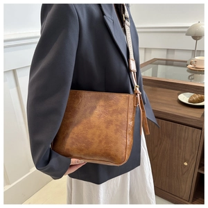 Detailed side view of caramel brown vintage bucket bag with adjustable woven shoulder strap
