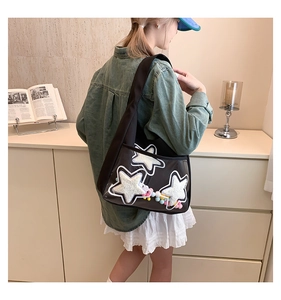 Détail du grand sac cabas noir avec étoiles en PVC transparent et pompons colorés