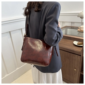 Model wearing a large burgundy oil-wax leather bucket bag in a professional office setting