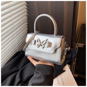 Close-up of silver crossbody bag with metallic butterfly buckle and rounded top handle