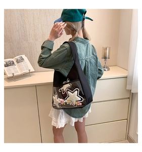 Détail du sac cabas noir avec poche PVC, étoiles en peluche et pompons colorés