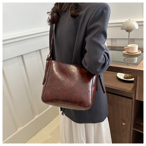 Detail view of burgundy leather shoulder bag showing glossy texture and side buckle