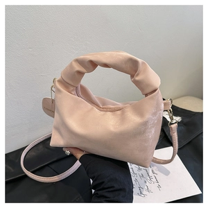 Detail of light pink pleated handbag with cloud-style handle and detachable shoulder strap