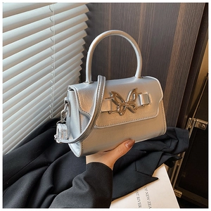 Detail of silver crossbody bag with golden butterfly buckle and sleek metallic finish