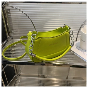 Detail of neon green leather tote bag with thick silver chain on display shelf