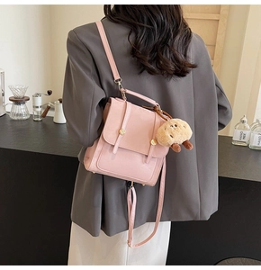 Detail of pink vintage faux leather backpack with metallic buckles and plush bear charm