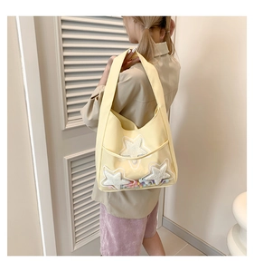 Détail du sac cabas jaune clair avec étoiles scintillantes et pompons colorés en PVC