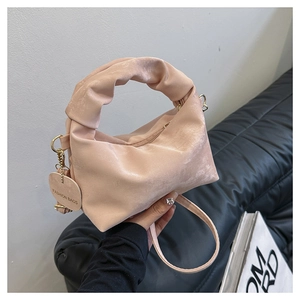 Detail of pink pleated handbag with fashion charm and slim shoulder strap