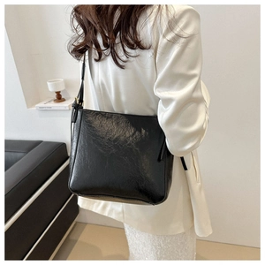 On-shoulder view of the black large capacity leather tote bag styled with a white blazer