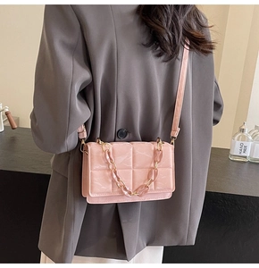 Détail d'un sac à bandoulière matelassé rose brillant avec une chaîne décorative