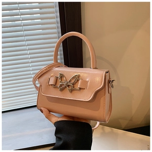 Detail of pink patent leather mini handbag featuring a silver butterfly buckle and glossy finish