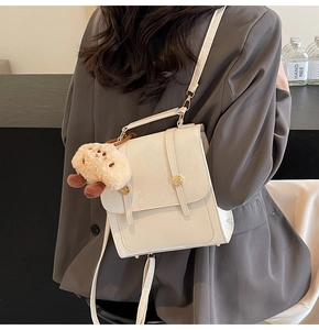 Detail of cream white PU backpack with gold rivets and cute brown plush charm