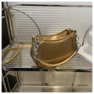 Detail of a chic gold metallic crescent handbag with silver chain and thick padded handle