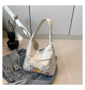 Vue détaillée du sac en toile blanc avec étoiles en peluche et pompons colorés à l'intérieur