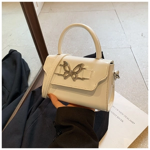 Detail of white mini crossbody bag featuring a large silver butterfly metal buckle