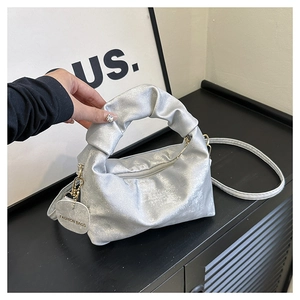Detail view of silver pleated handbag with unique cloud handle and metal fashion tag