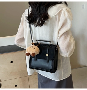 Model view of black leather backpack with bear pendant and gold buckle details