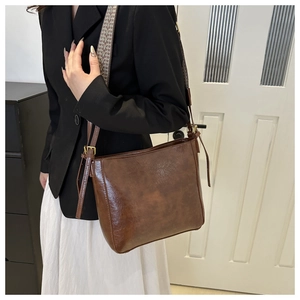 Detail of vintage brown oily leather bucket bag with bohemian geometric wide strap