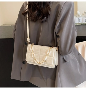 Détail du petit sac bandoulière matelassé blanc crème avec chaîne dorée sur blazer