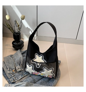 Détail du sac cabas noir avec étoiles et boules en peluche dans une poche PVC claire