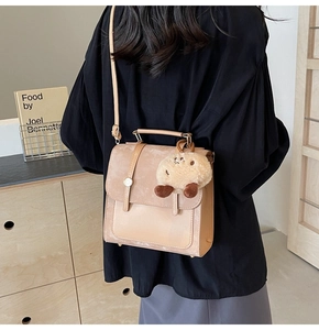 Detail of vintage beige crossbody bag with plush charm and mixed leather texture finish