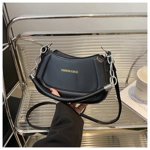 Detail of black leather half-moon bag with gold fashion lettering and metal chain links