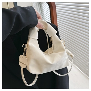 Detail of white knotted handbag in soft PU leather with gold accents and fashion tag