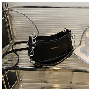 Detail of black moon bag with silver chain strap and cylindrical handle on glass shelf