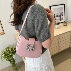 Sac hobo rose avec boucle en cristal présenté dans un décor moderne chic