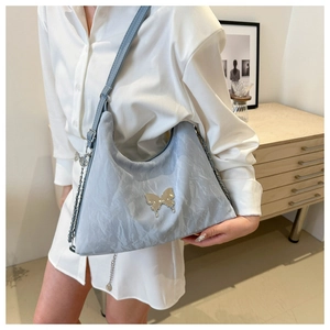 Détail du sac à bandoulière en tissu froissé bleu clair avec décoration papillon argenté